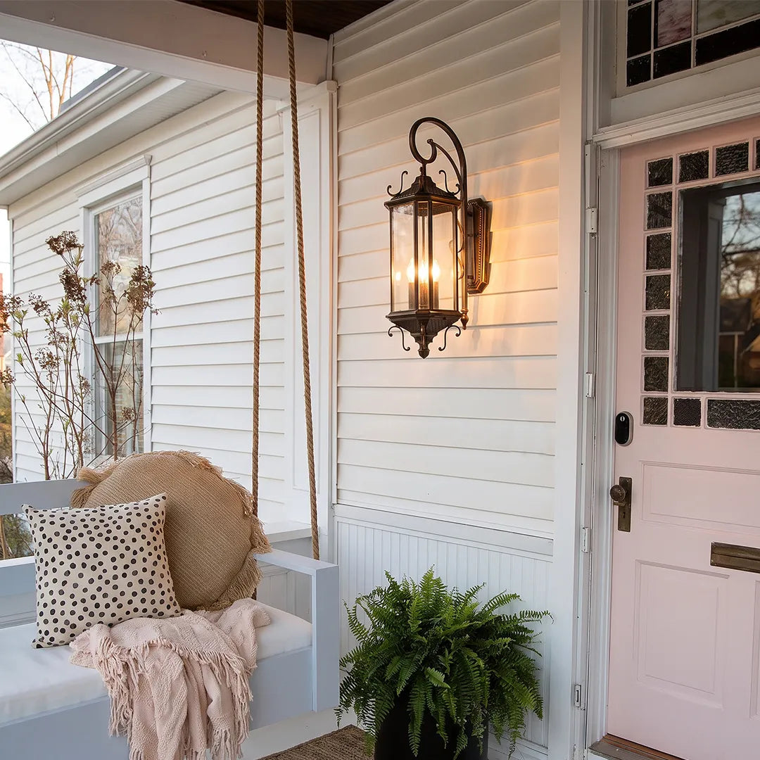 Black outdoor lantern sconce mounted on white siding next to a porch chair, creating a welcoming and traditional outdoor entryway.