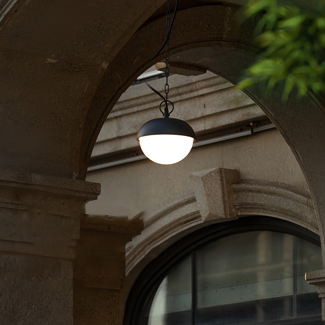 Black outdoor pendant light installed under an arched exterior structure, offering soft ambient glow.