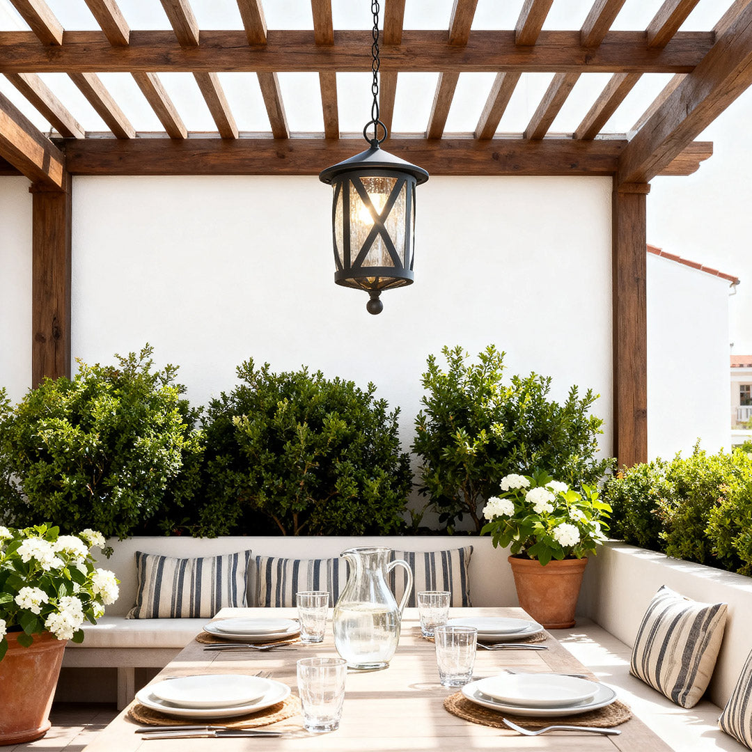 Black outdoor pendant light illuminating wooden pergola dining area with outdoor table setting