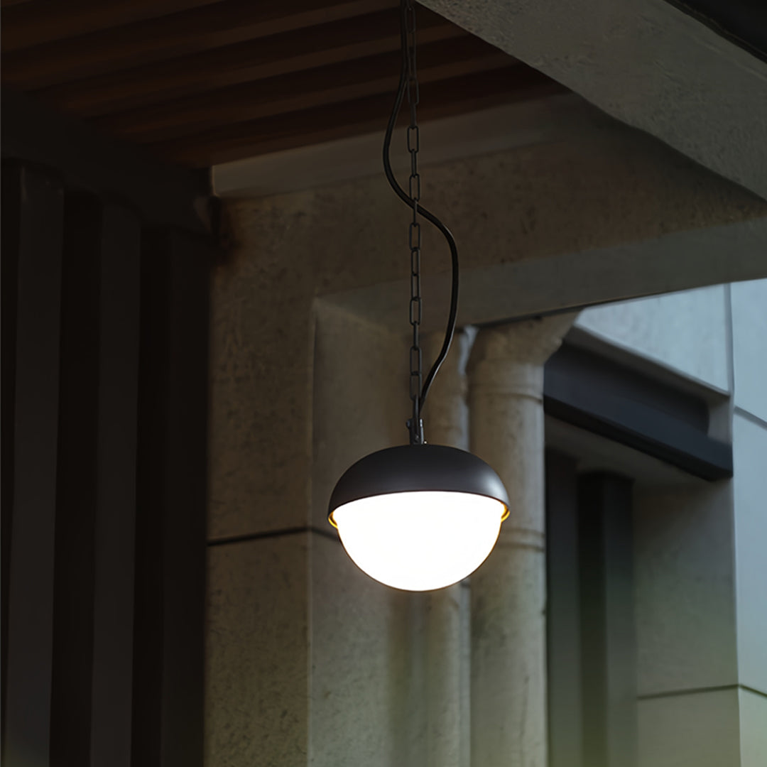 Contemporary black outdoor pendant light mounted beneath a ceiling eave, creating cozy exterior lighting.
