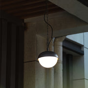 Contemporary black outdoor pendant light mounted beneath a ceiling eave, creating cozy exterior lighting.