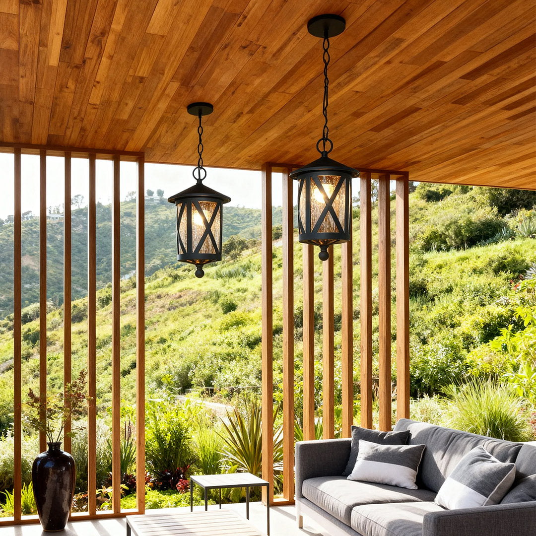 Black outdoor pendant light hanging from wood-paneled ceiling over modern outdoor lounge with mountain views