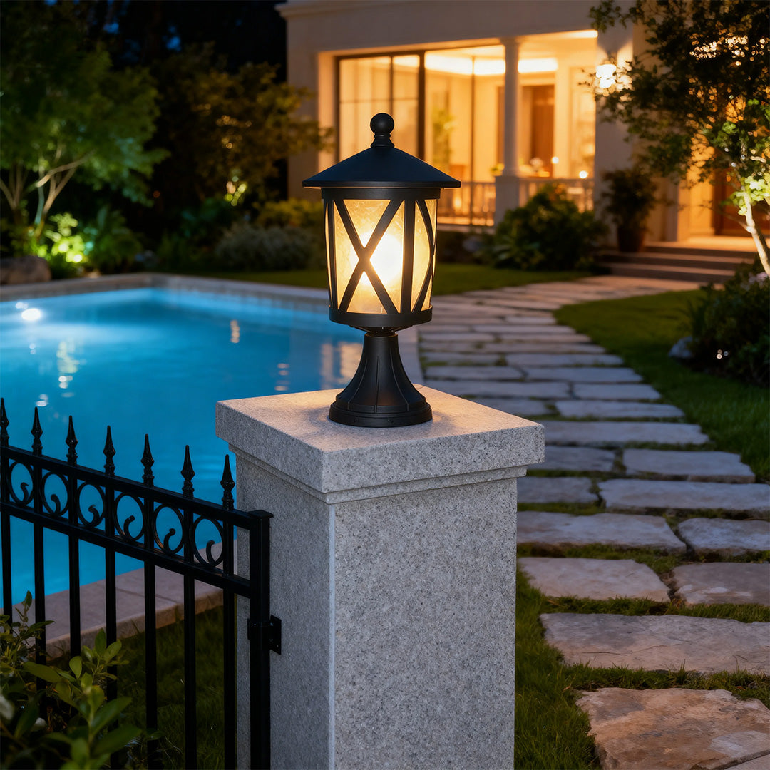 Black outdoor pillar light glowing warmly on grey granite post beside elegant poolside stairway at dusk