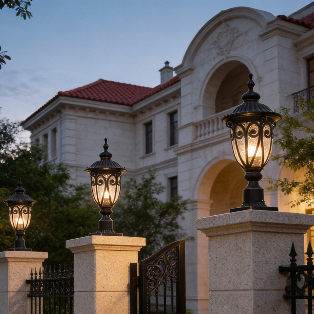 Elegant black outdoor pillar light illuminating the entrance of a luxurious villa with warm glow.