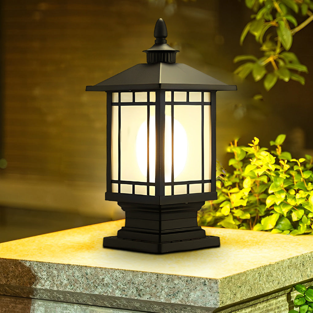 Black outdoor street light pillar illuminating landscaped garden area at night.