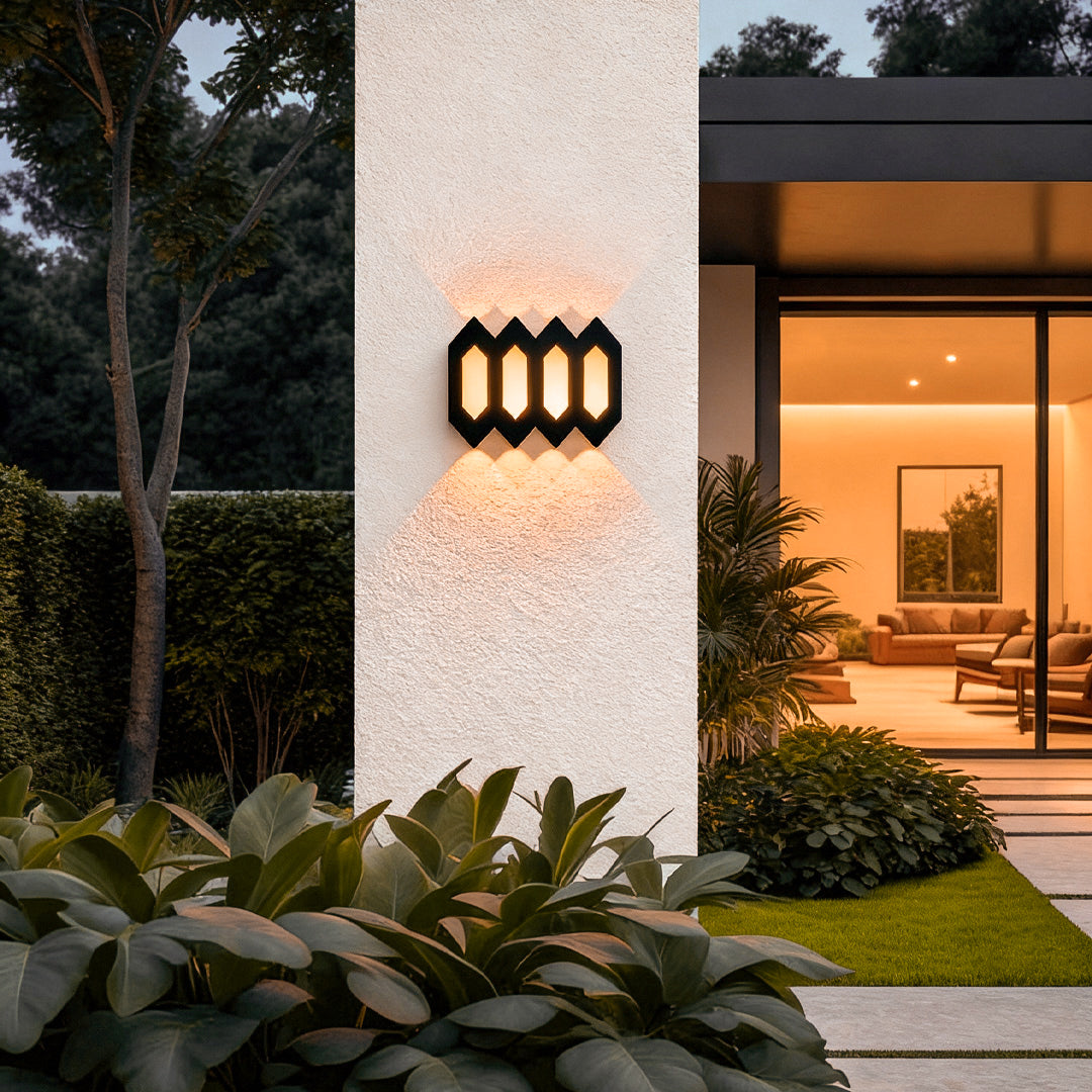 Black outdoor up and down wall lights mounted on a white exterior wall, illuminating an outdoor entry area with warm light.
