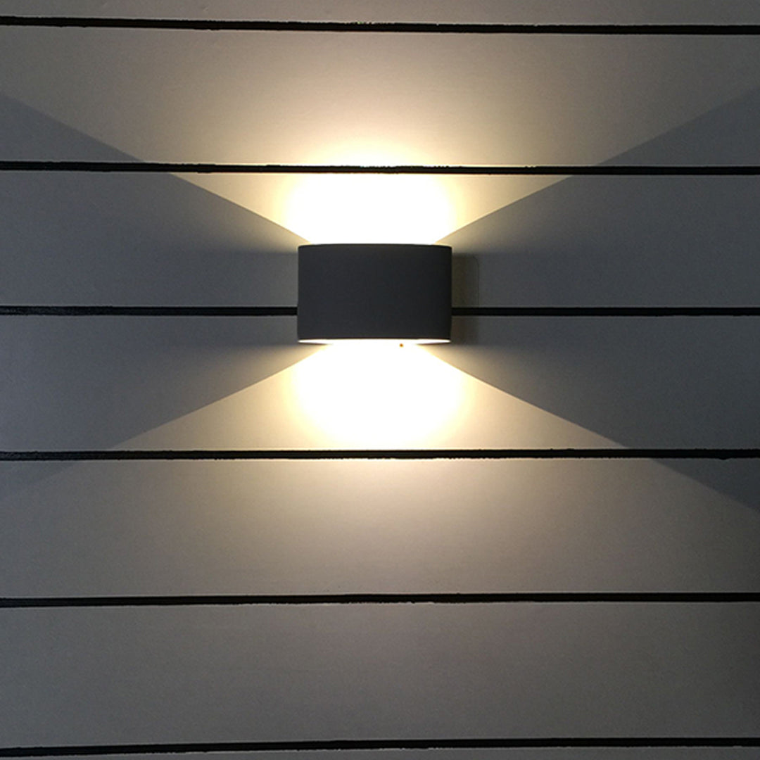 Black outdoor up down wall light creating focused beam patterns on modern exterior
