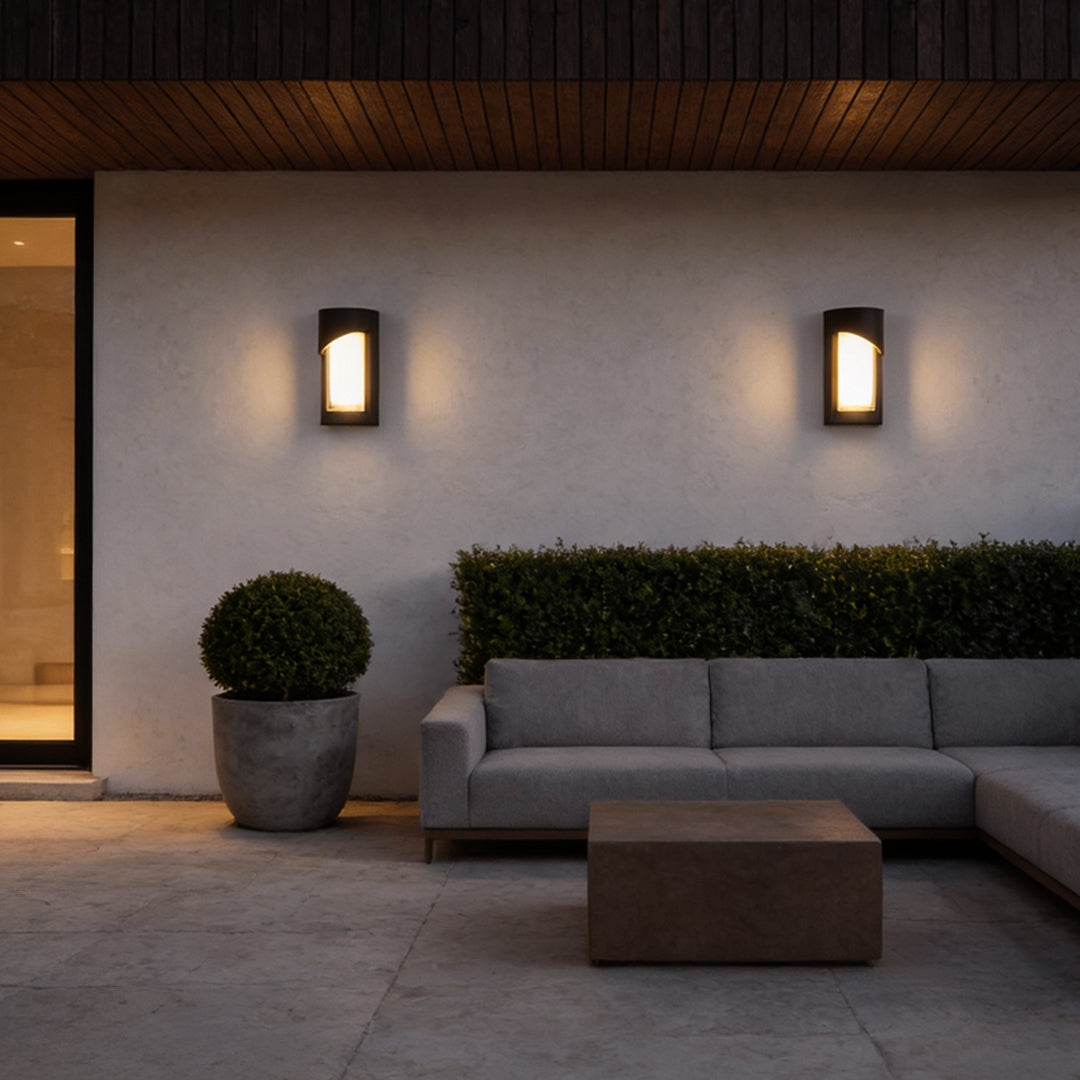 Black outdoor wall light providing ambient lighting for cozy outdoor seating area.
