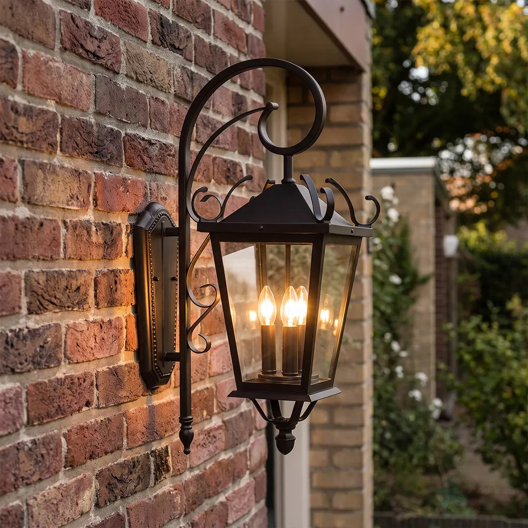 Black outdoor wall light mounted on a red brick wall, showcasing a classic lantern design with a curved scroll arm.