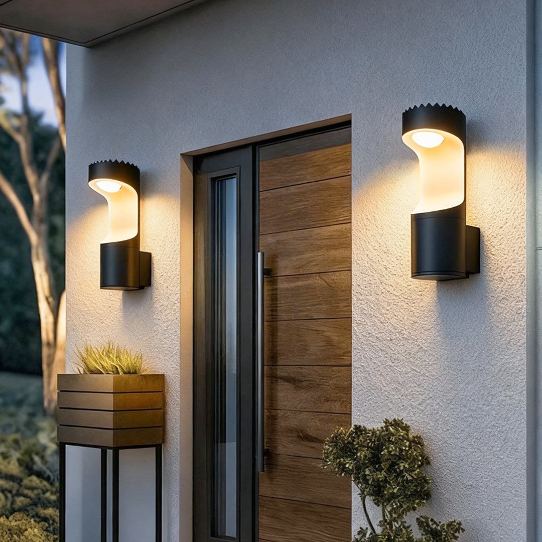 Black outdoor wall sconce lighting fixtures illuminating a modern home exterior with warm light.