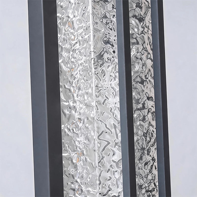 Black outside wall lights close-up highlighting the decorative textured glass between slim black metal bars.