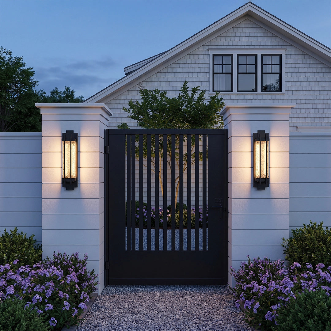 Black outside wall lights flanking a modern garden gate with warm nighttime illumination.