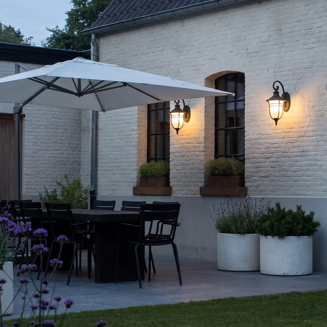 Black outside wall lights providing warm patio lighting beside windows and an outdoor dining area.