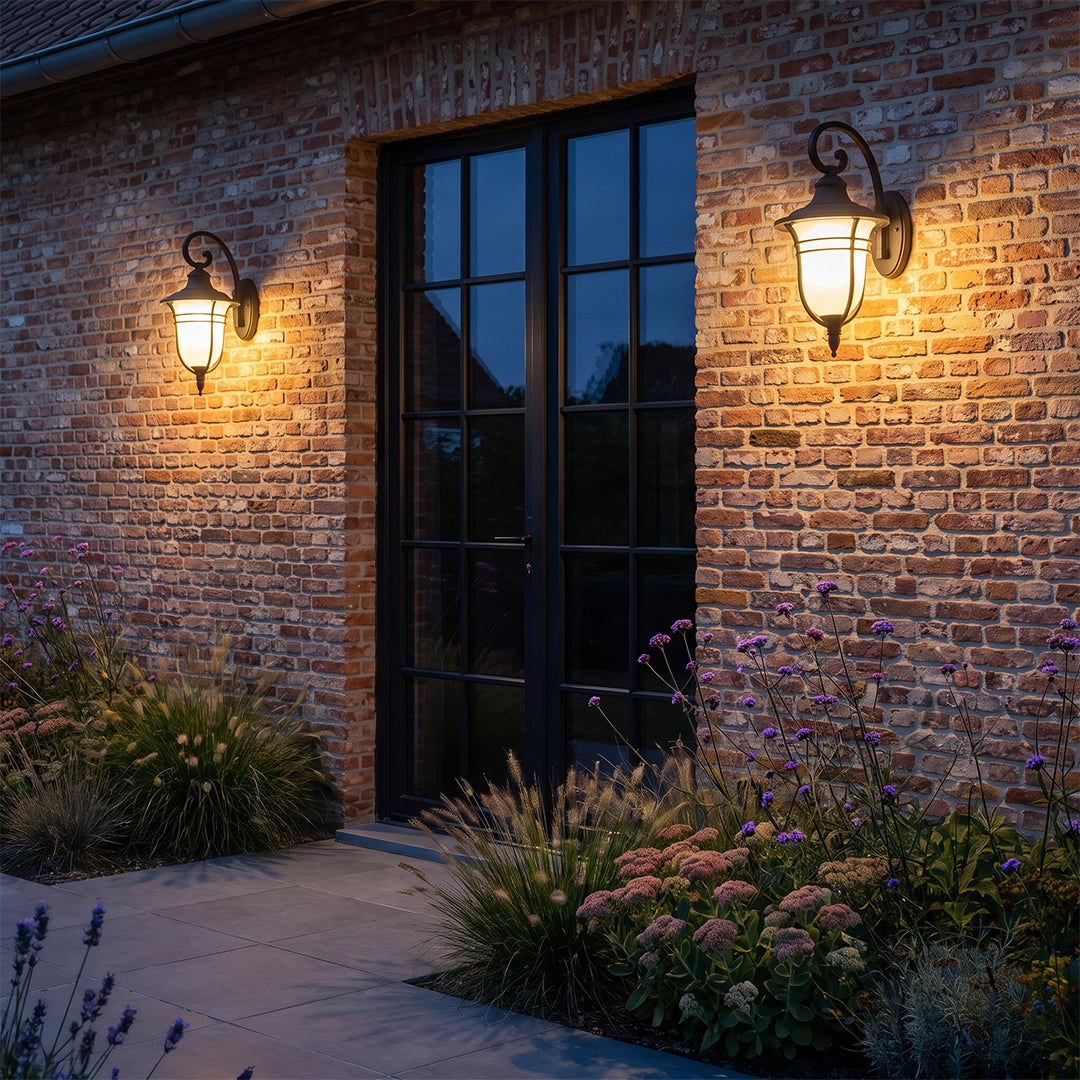 Black outside wall lights casting warm illumination beside tall windows on a red brick exterior.