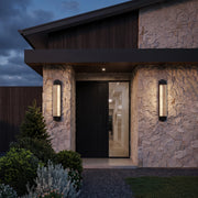 Black outside wall lights installed beside a contemporary stone home entrance for warm illumination.