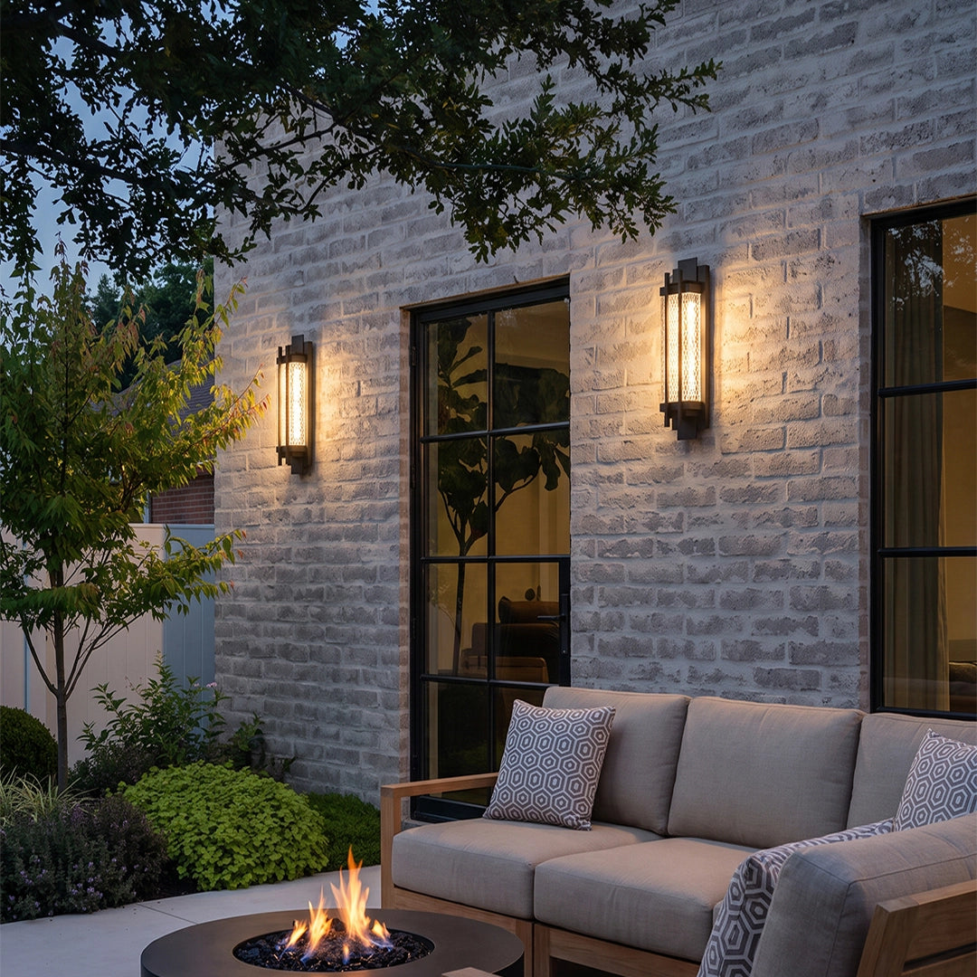 Black outside wall lights illuminating a modern stone patio with outdoor seating and a fire pit.