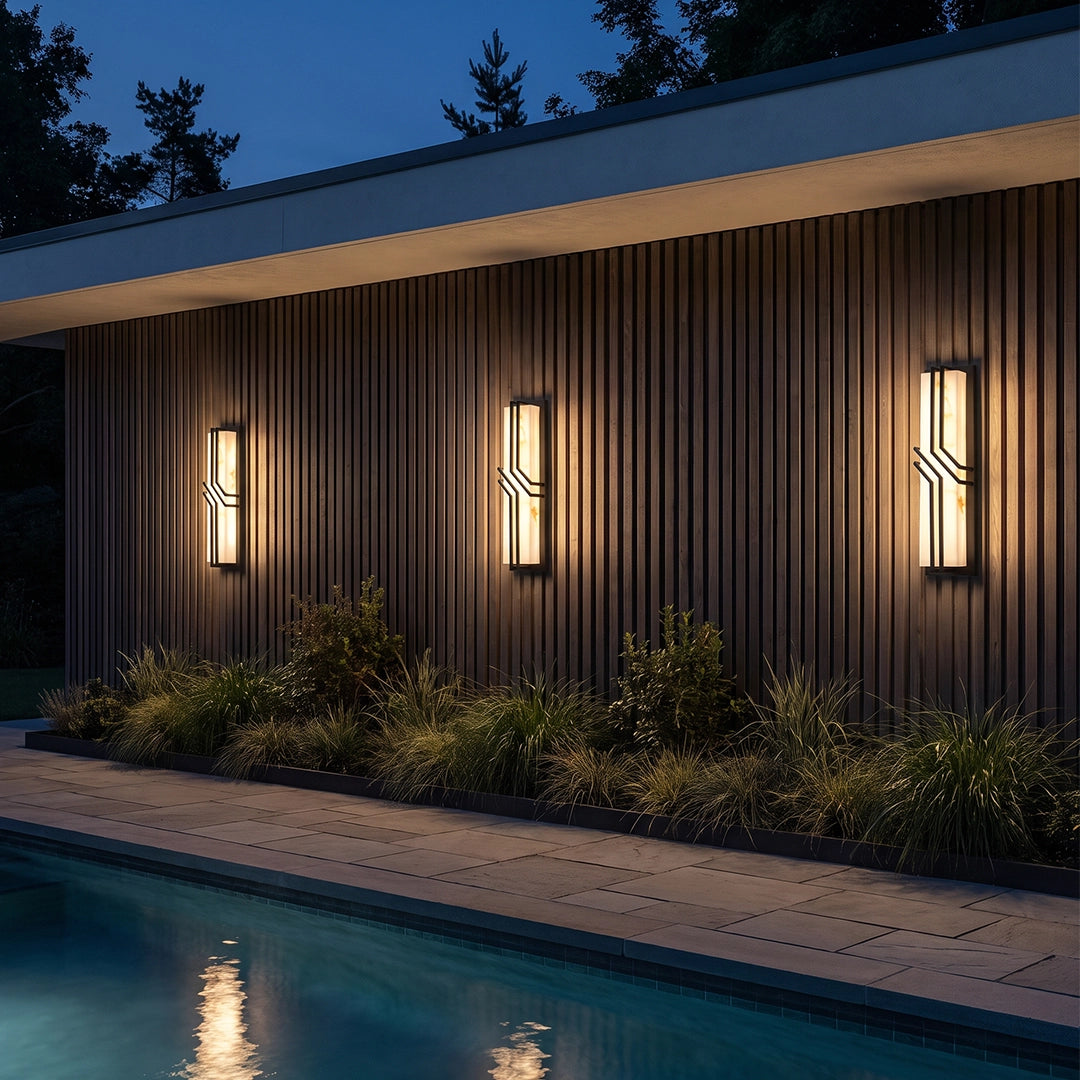 Black outside wall lights illuminating a stone patio with outdoor seating and a fire pit.
