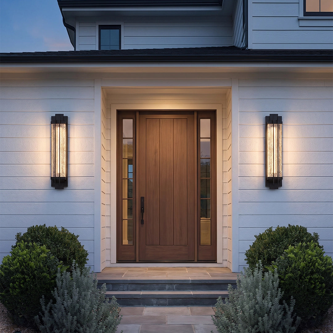 Black outside wall lights mounted on both sides of a wooden front door on a white brick exterior.
