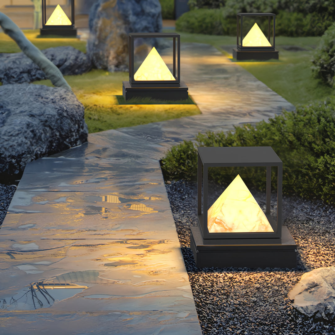 Multiple glowing pyramid outdoor lamps placed on stone steps highlighting modern light pillar design.