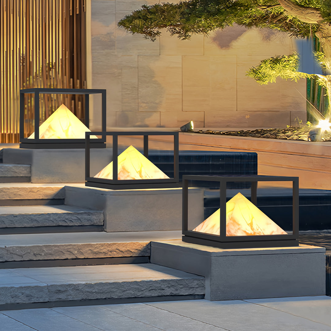 Garden pathway illuminated by several pyramid-shaped lamps featuring contemporary light pillar design.