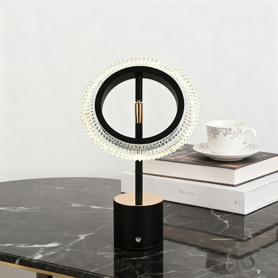 Black ring table lamp featuring a circular crystal shade and copper accent on a luxurious black marble countertop.