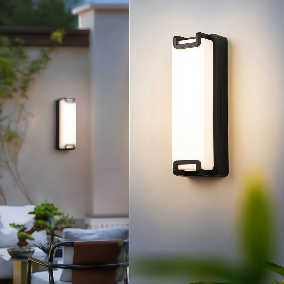 Black outdoor wall sconce on a contemporary home exterior, casting ambient light to highlight the modern architectural details.
