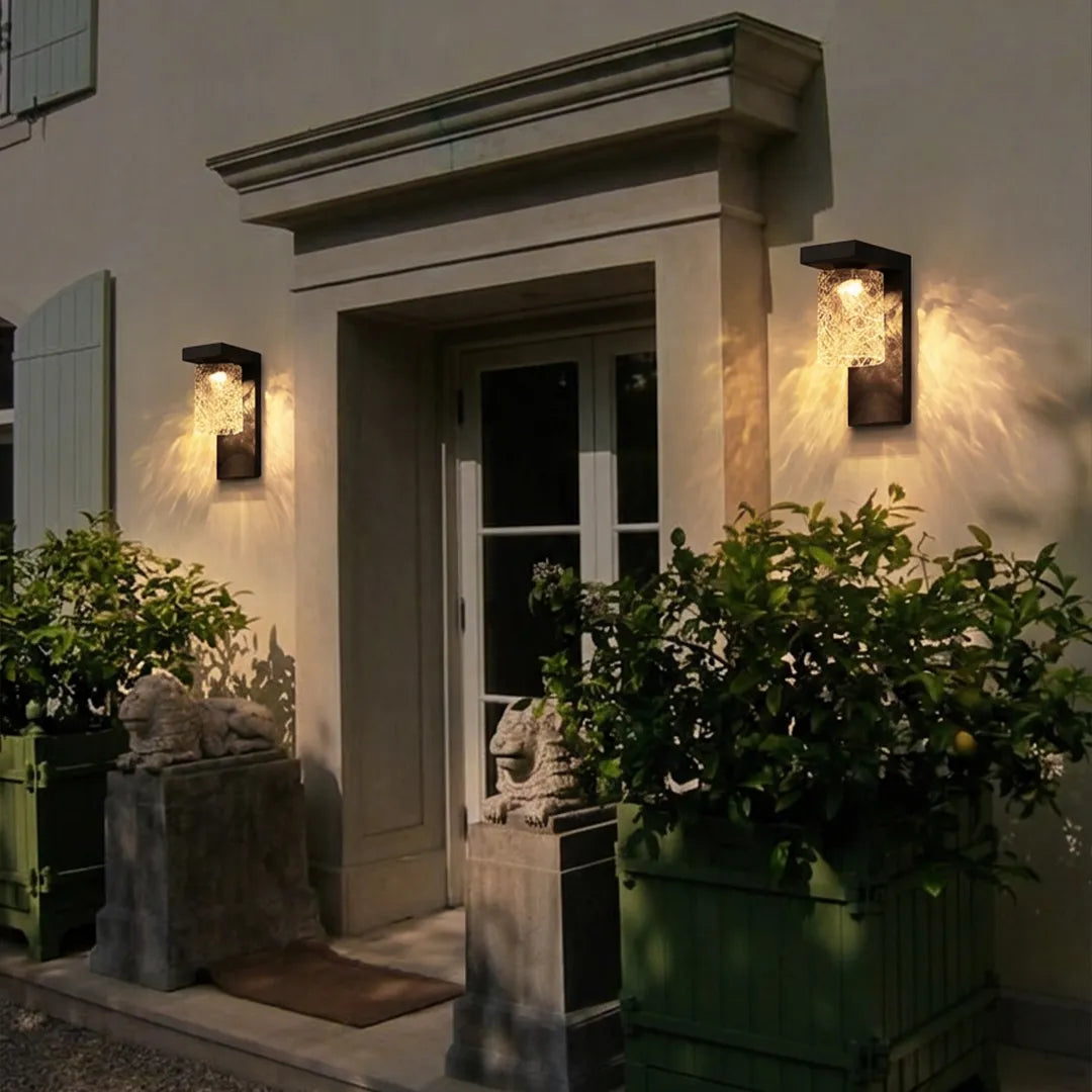 Black sconce wall light flanking a classic exterior doorway with textured glass illumination.