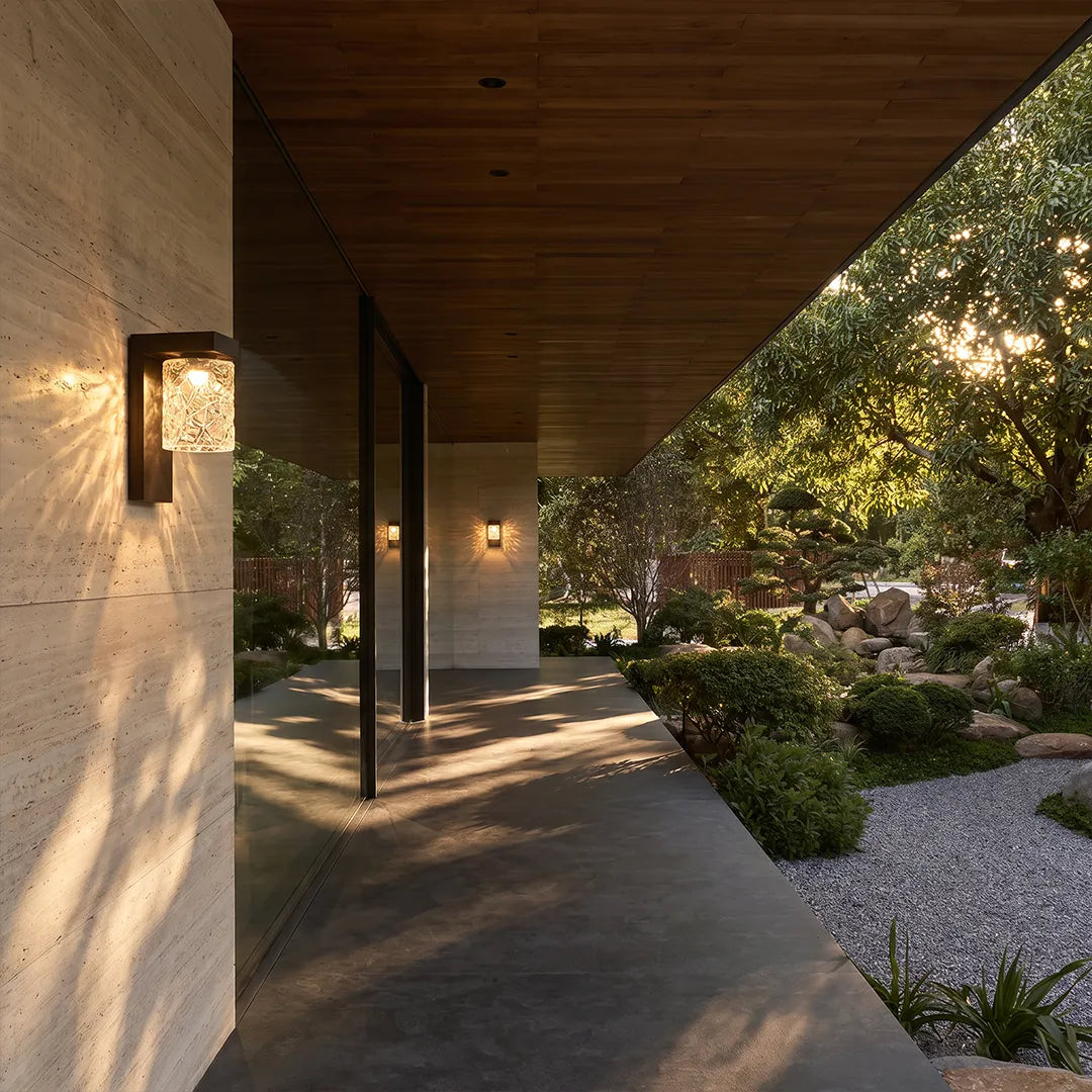Black sconce wall light lining a covered outdoor walkway with warm ambient lighting.