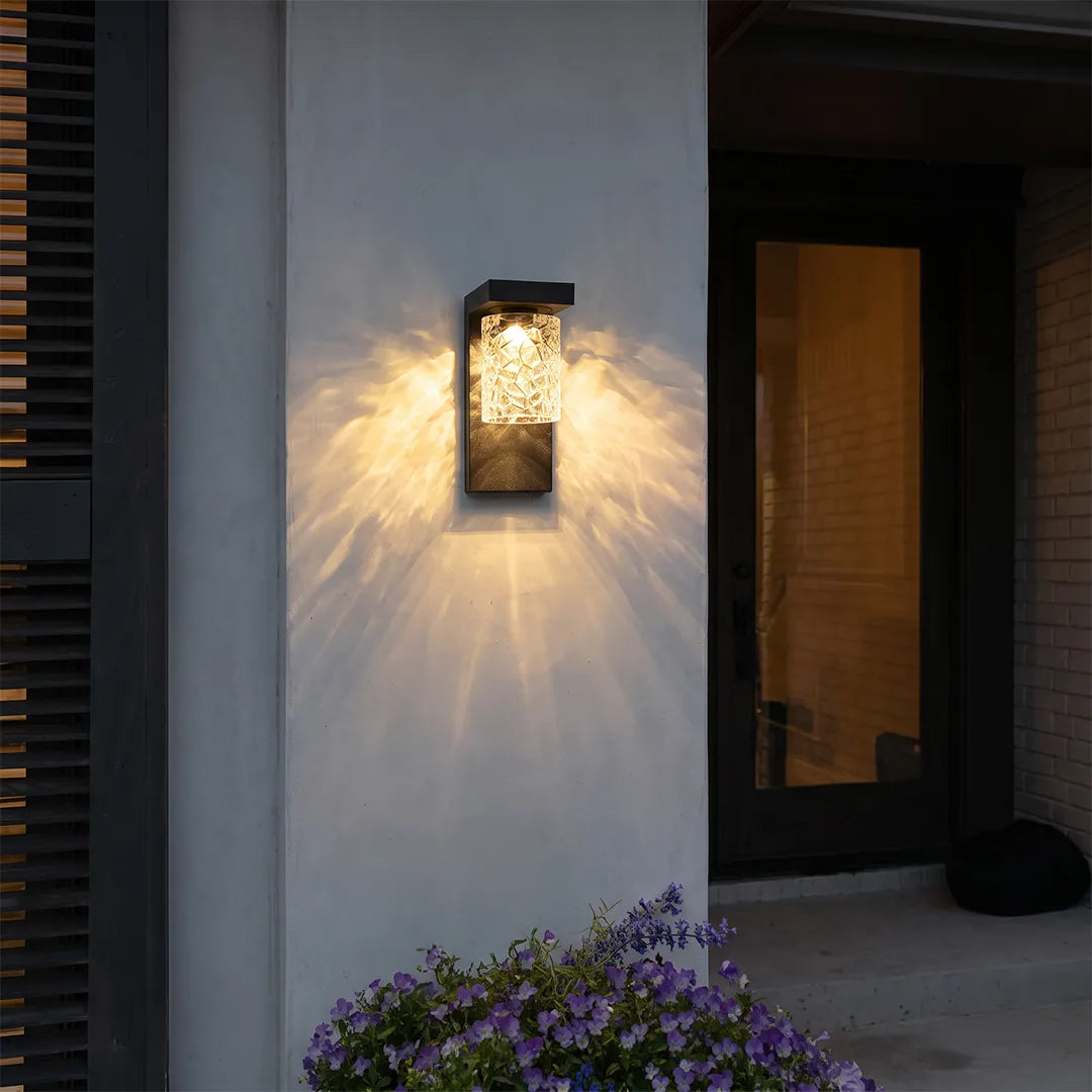 Black sconce wall light mounted beside a modern front door with warm decorative glow.