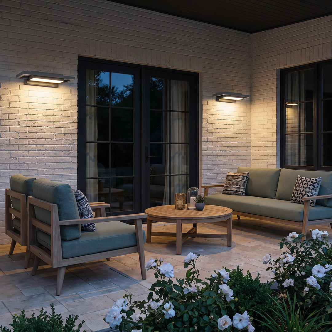 Black sconce wall lights illuminating a covered outdoor patio with stone walls and seating.