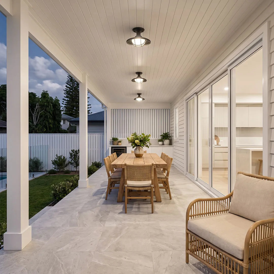 Black semi flush ceiling lights installed along a covered patio dining area with white columns.