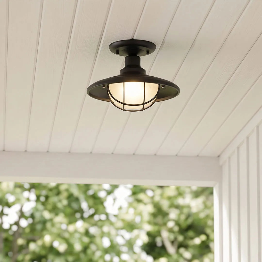 Black semi flush ceiling light mounted on a white porch ceiling above an outdoor entry.