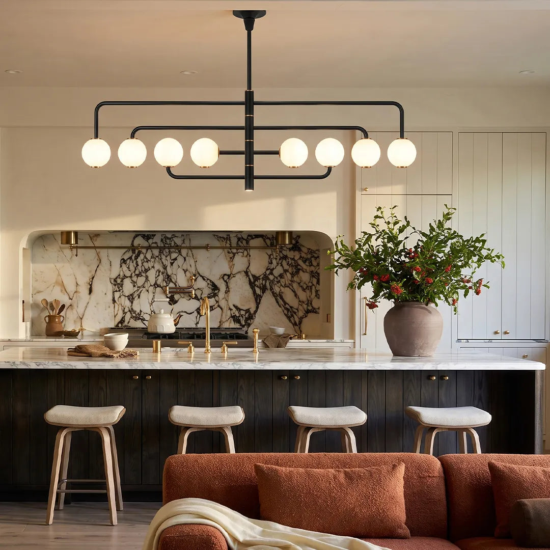 Black semi flush mount light installed above a kitchen island in a modern kitchen with marble backsplash and bar stools.