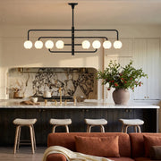 Black semi flush mount light installed above a kitchen island in a modern kitchen with marble backsplash and bar stools.