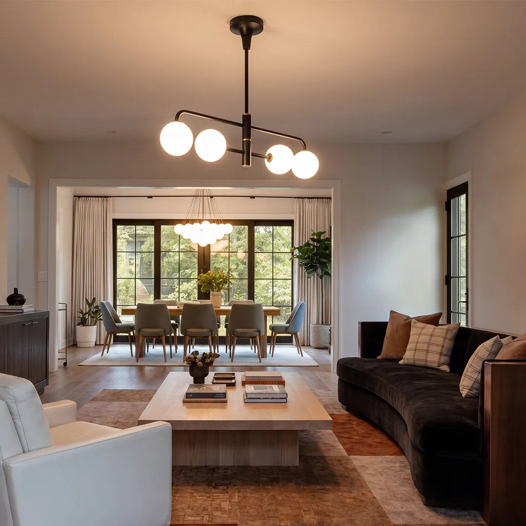 Black semi flush mount light hanging in a warm living room that opens to a dining area through large glass doors.