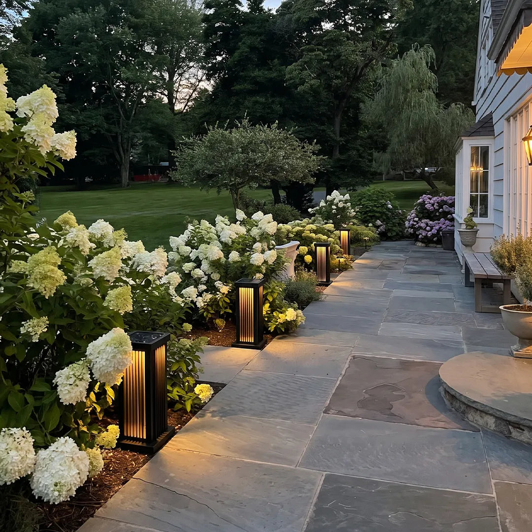 Black solar pillar lights guiding a flagstone walkway through blooming white hydrangeas