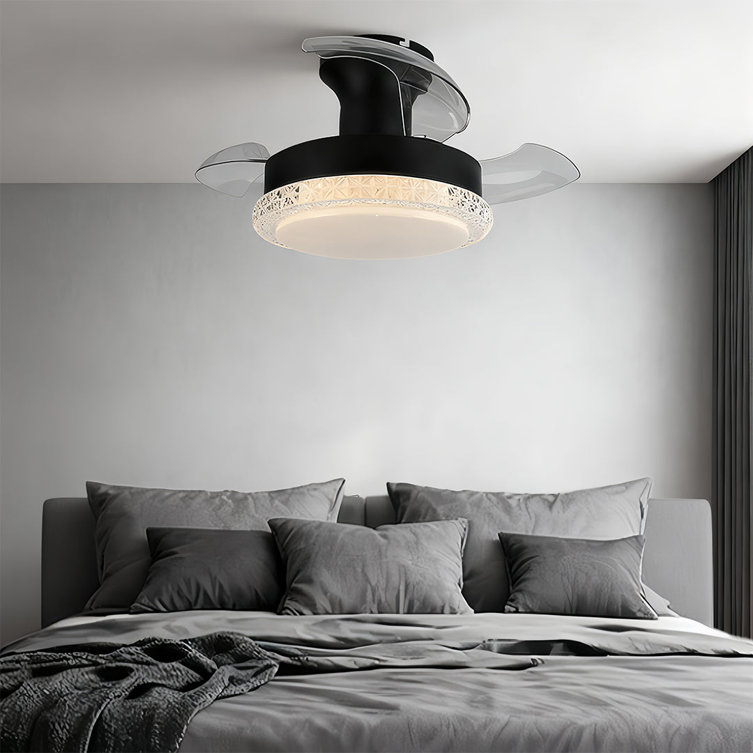 Black three blade ceiling fan with light creating ambient lighting in modern grey bedroom with dark accents.
