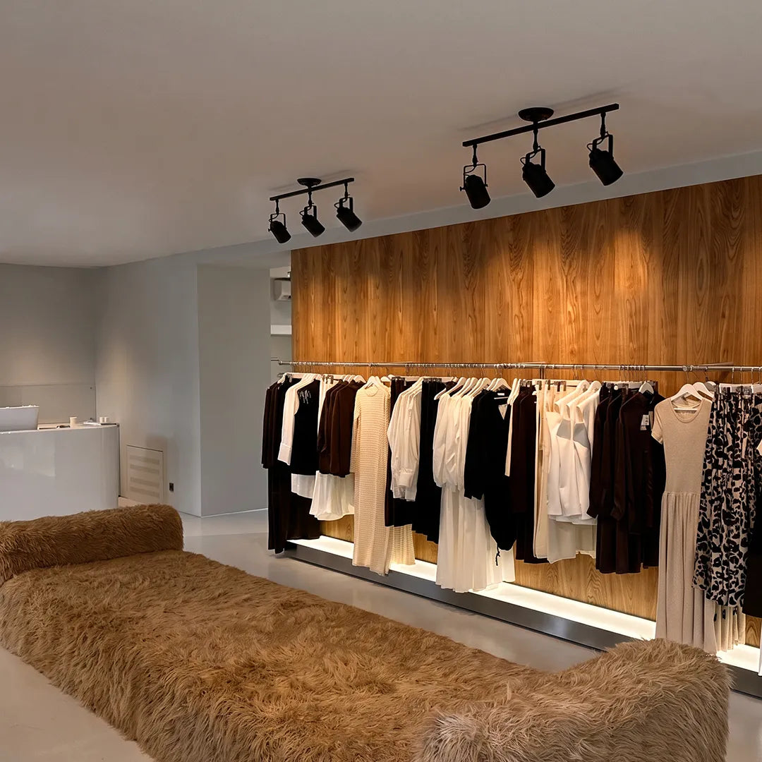 Black track light with multiple adjustable heads illuminating clothing displays in a retail store.