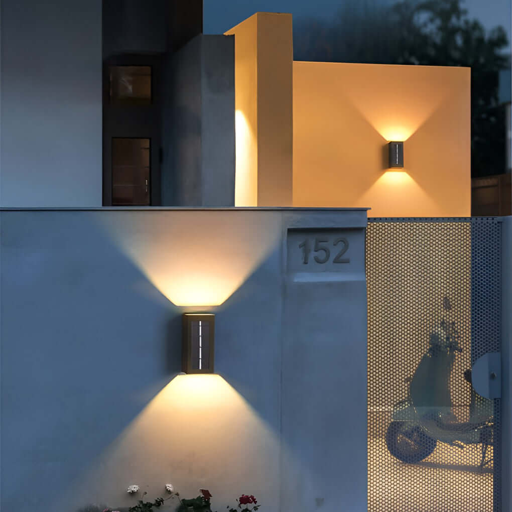 Black up down wall light illuminating residential house facade