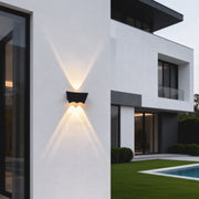 Black up down wall light installed on a modern exterior facade, casting symmetrical light beams to highlight architectural lines.