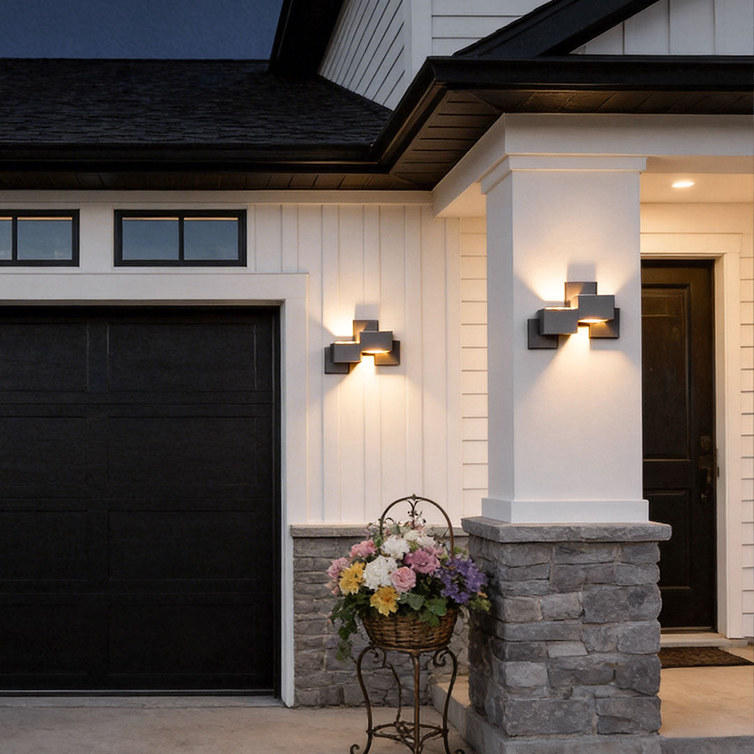 Black up down wall lights with a sleek design, illuminating a house entrance at night.