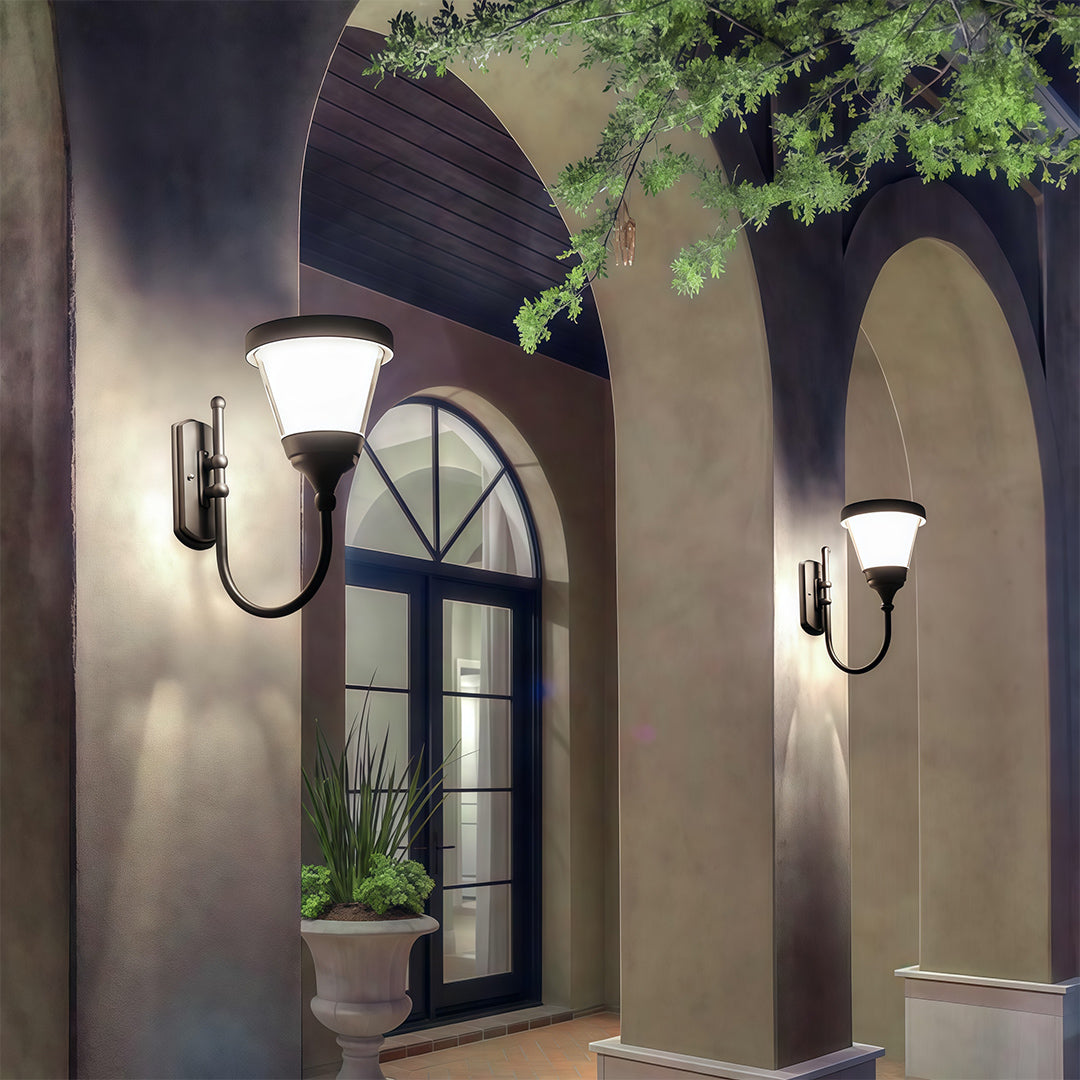 Black outdoor wall mount light shining over a stone pathway, enhancing the nighttime outdoor ambiance.
