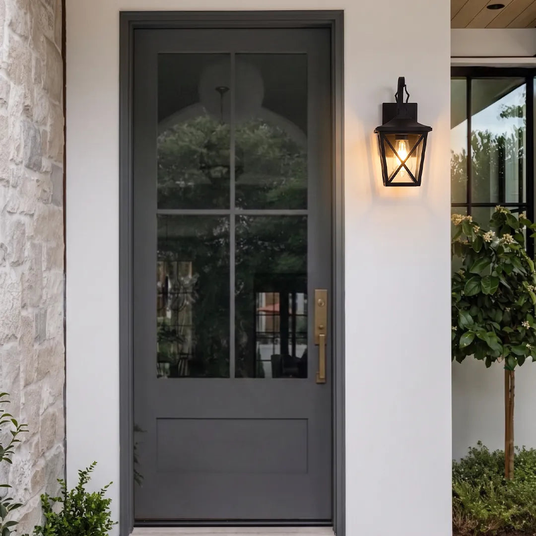 Black wall lighting mounted beside a gray exterior door, adding classic lantern-style illumination to the entryway.