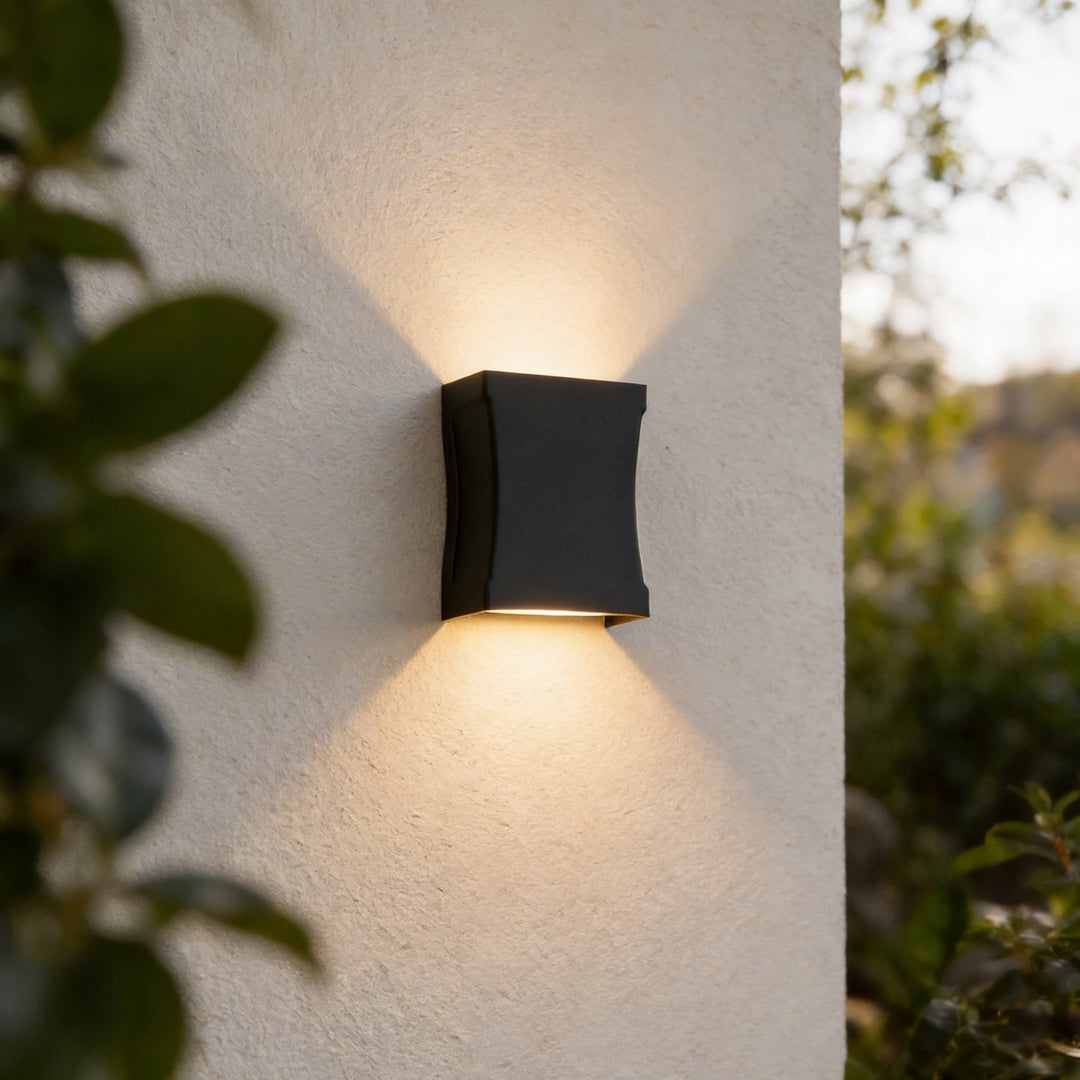 Black wall lights mounted on a white exterior wall, casting warm up and down beams.