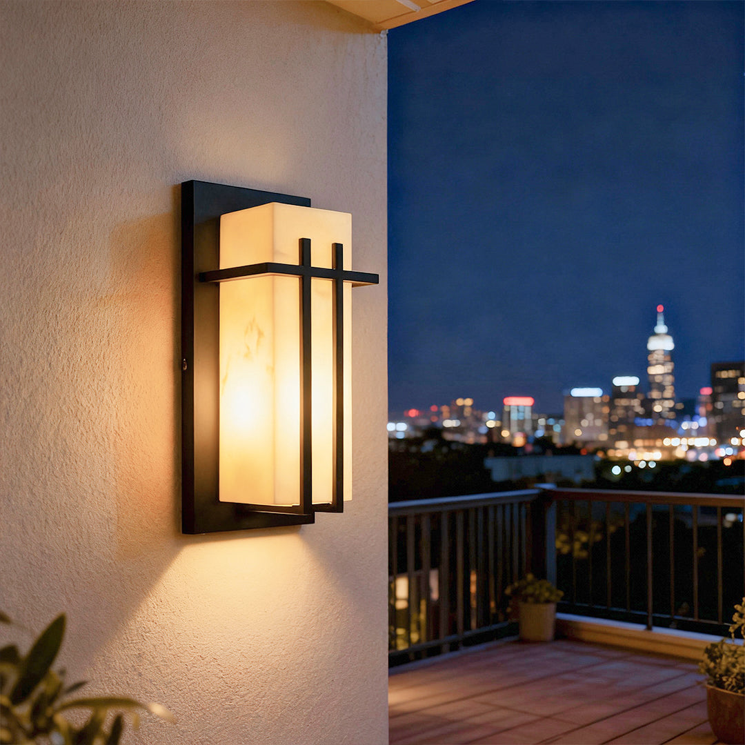Black wall lights providing evening illumination on outdoor patio with city skyline view in background