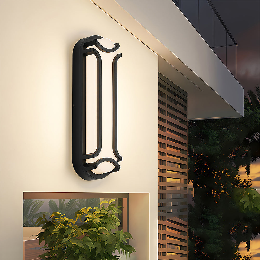 Black outdoor wall sconce with a frosted diffuser, illuminating an entryway with a clean and minimalistic design.