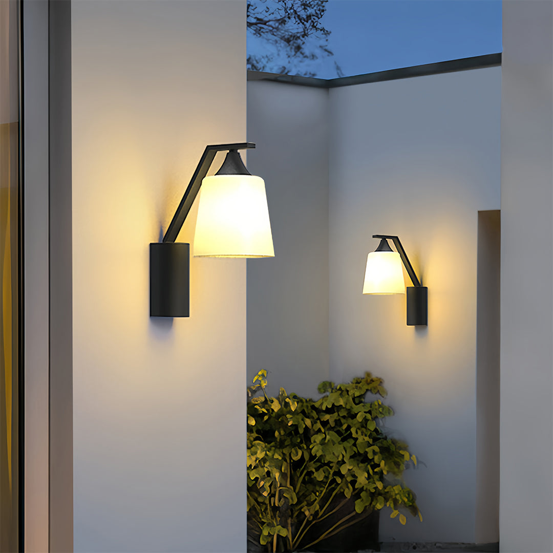 Outdoor wall-mounted black sconce casting a warm glow, enhancing the exterior ambiance of a modern home.