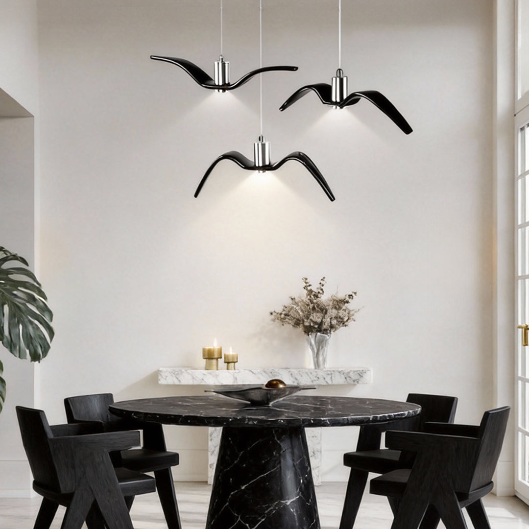 Black wing pendant light hanging over a minimalist dining table.