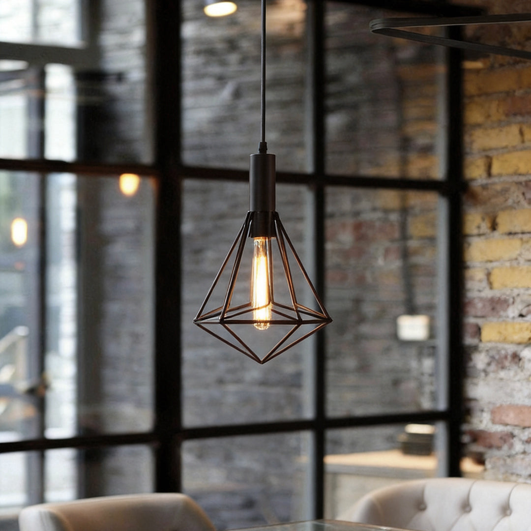 Black wire cage pendant light illuminating a modern industrial dining area with warm, ambient glow.