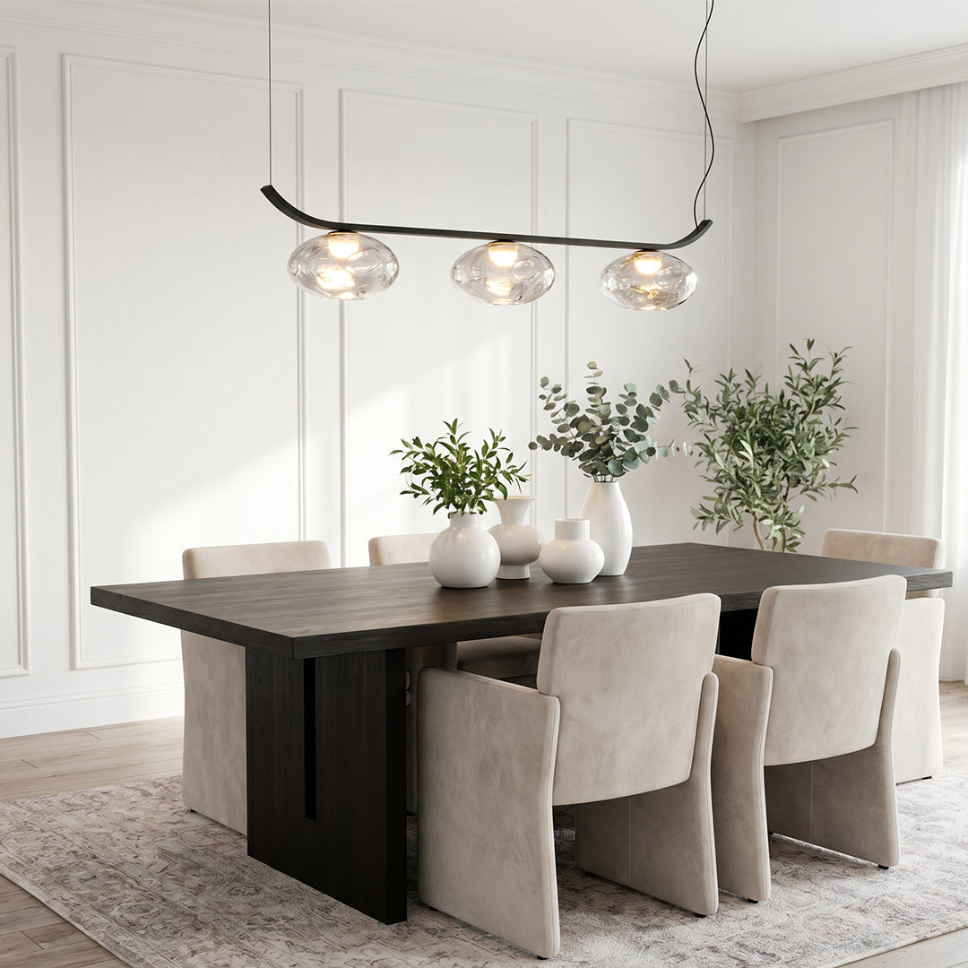 Black wrought iron chandelier above dining table in a modern minimalist interior.